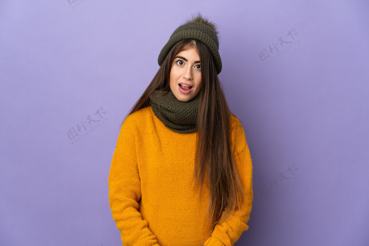人年轻的白人女孩 戴着冬天的帽子 在紫色的背景下 表情出奇地孤立着年轻天气欢呼