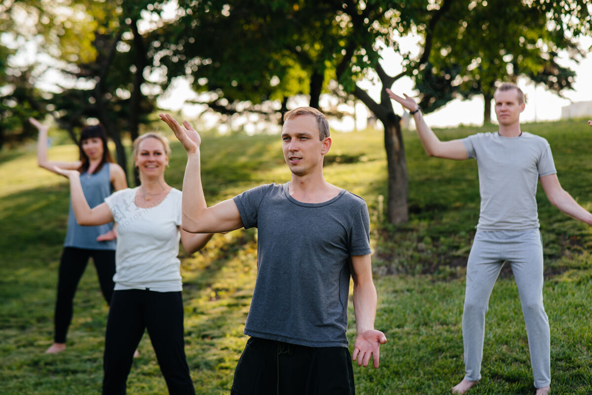 垫子一群人在日落时分在公园里做瑜伽健康的生活方式 冥想和健康朋友年轻身体