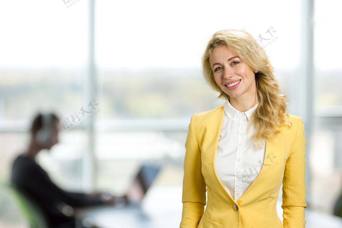 优雅开朗的女人坐在办公室的窗户上穿着时尚黄色夹克的漂亮的办公室经理在商务中心微笑着正式服装女士聪明