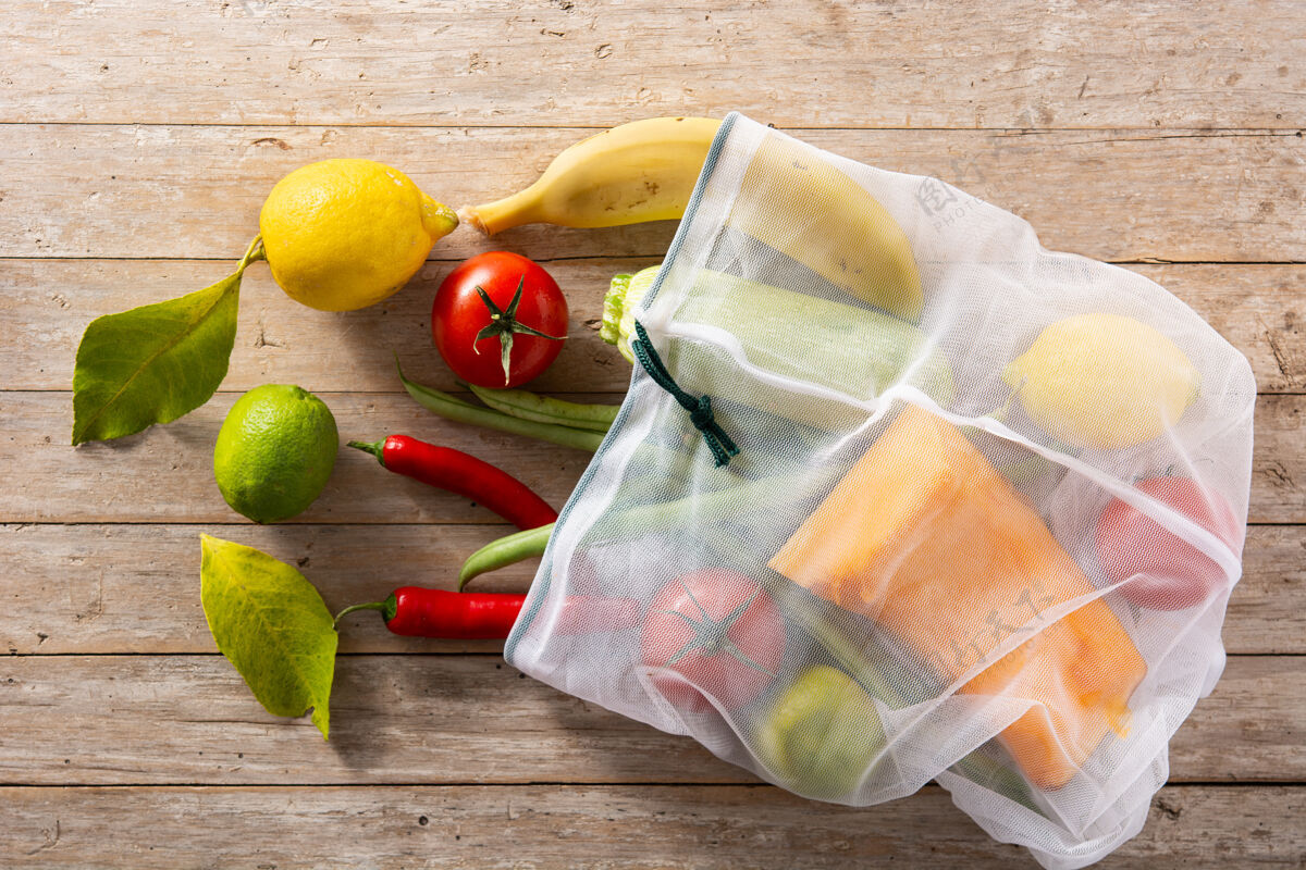 生的环保的可重复使用的购物袋与蔬菜和水果在木桌上南瓜木材西葫芦