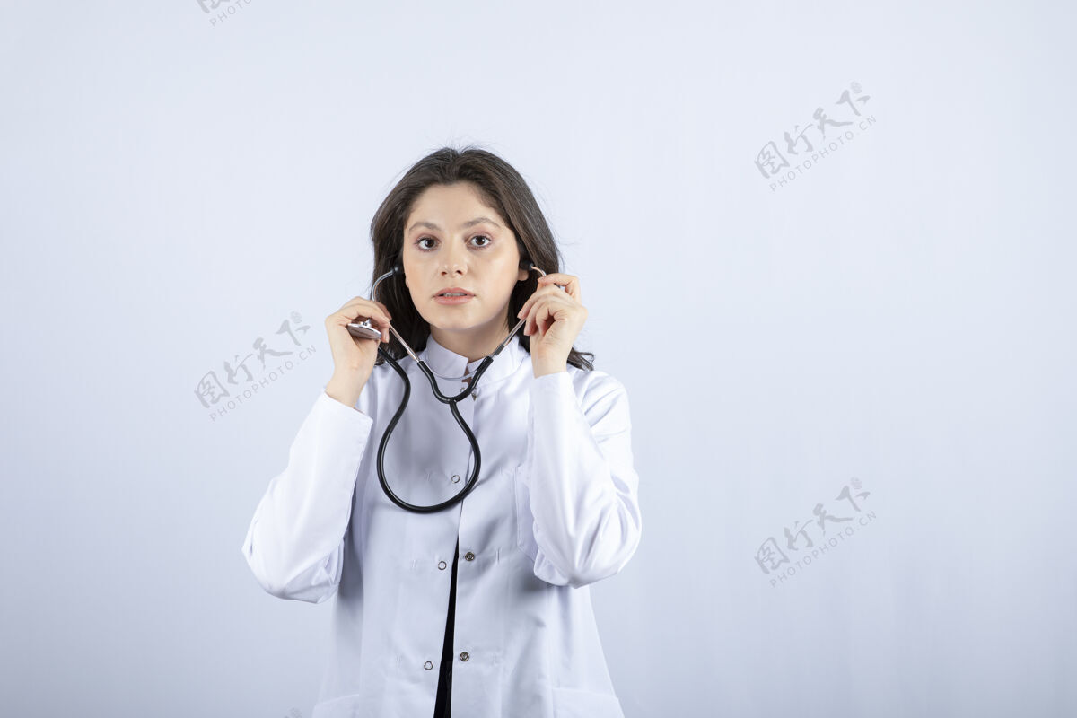 年轻人年轻女医生在白墙上用听诊器检查脉搏工作咨询治疗