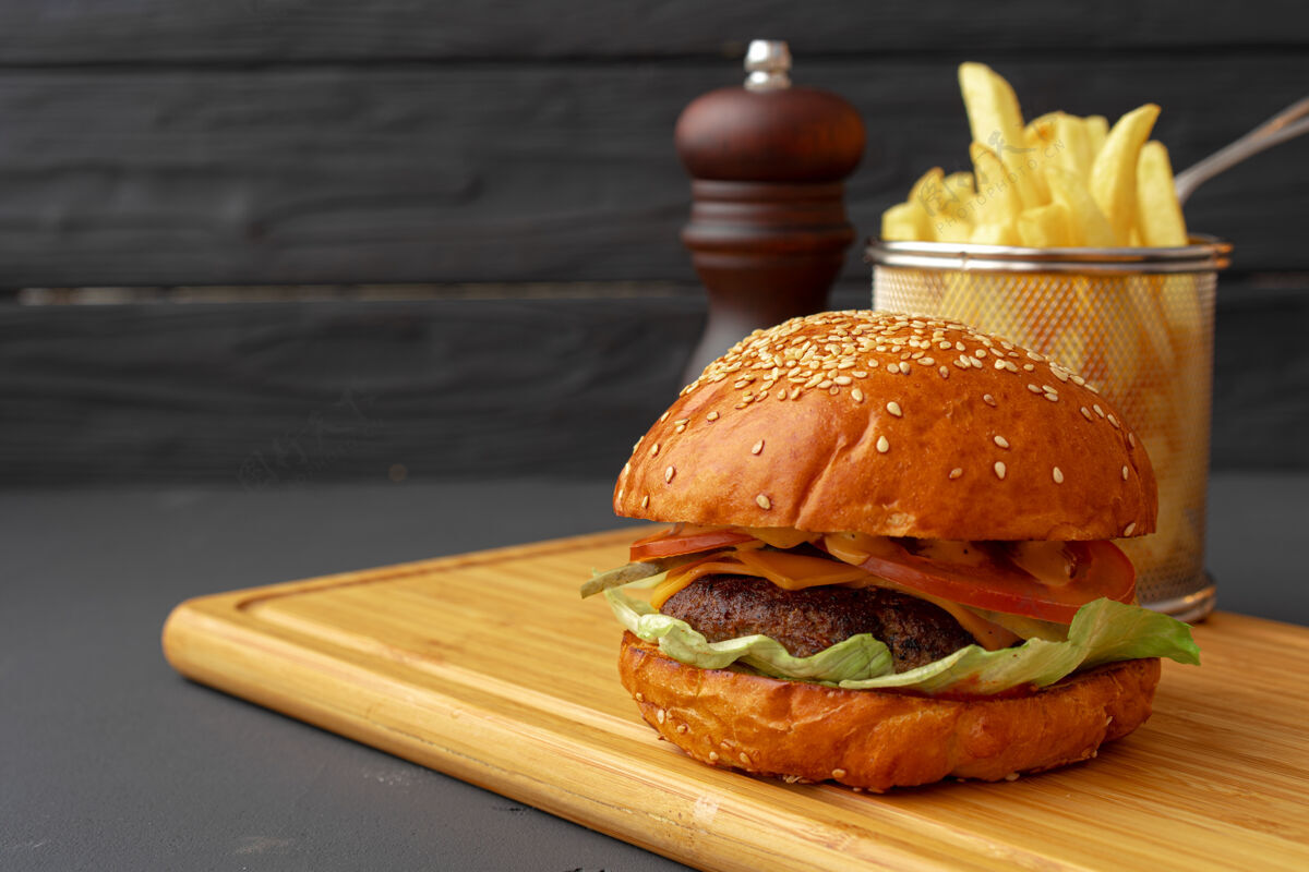 三明治美味的汉堡和炸薯条放在木板上贴着黑色的表面面包板美味