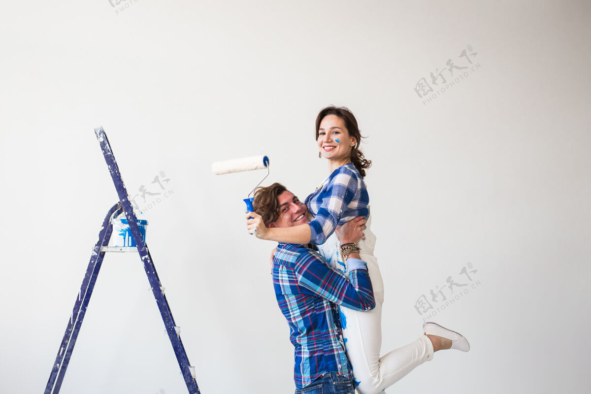 夫妻修缮 家庭和装修理念——站在梯子上的有趣的年轻男女衬衫搞笑工作