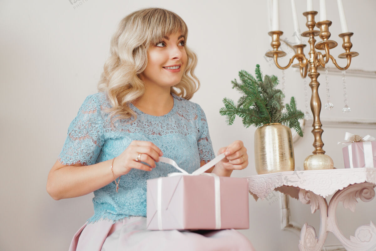 乐趣可爱的积极的女人靠近圣诞树打开礼物在粉红色的盒子积极微笑节日