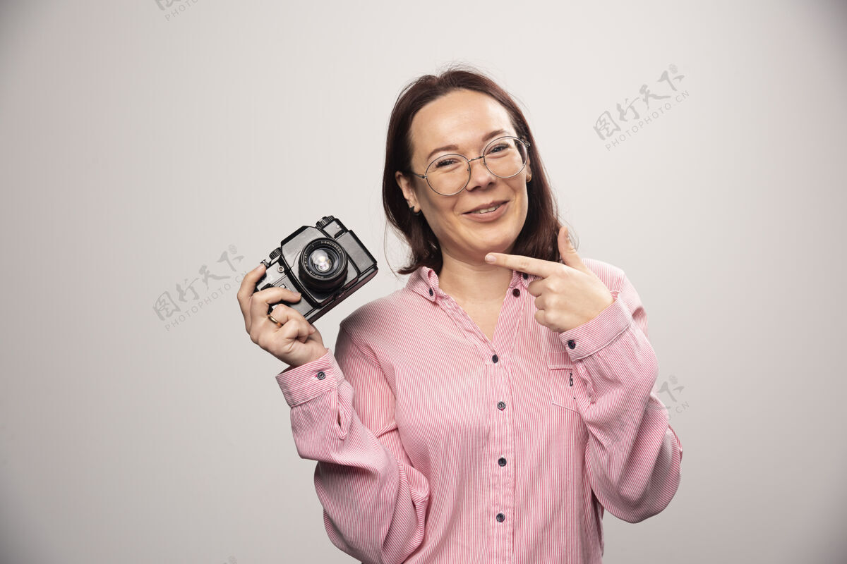 拍摄女人在一张高质量的白色照片上展示相机可爱漂亮摄影师