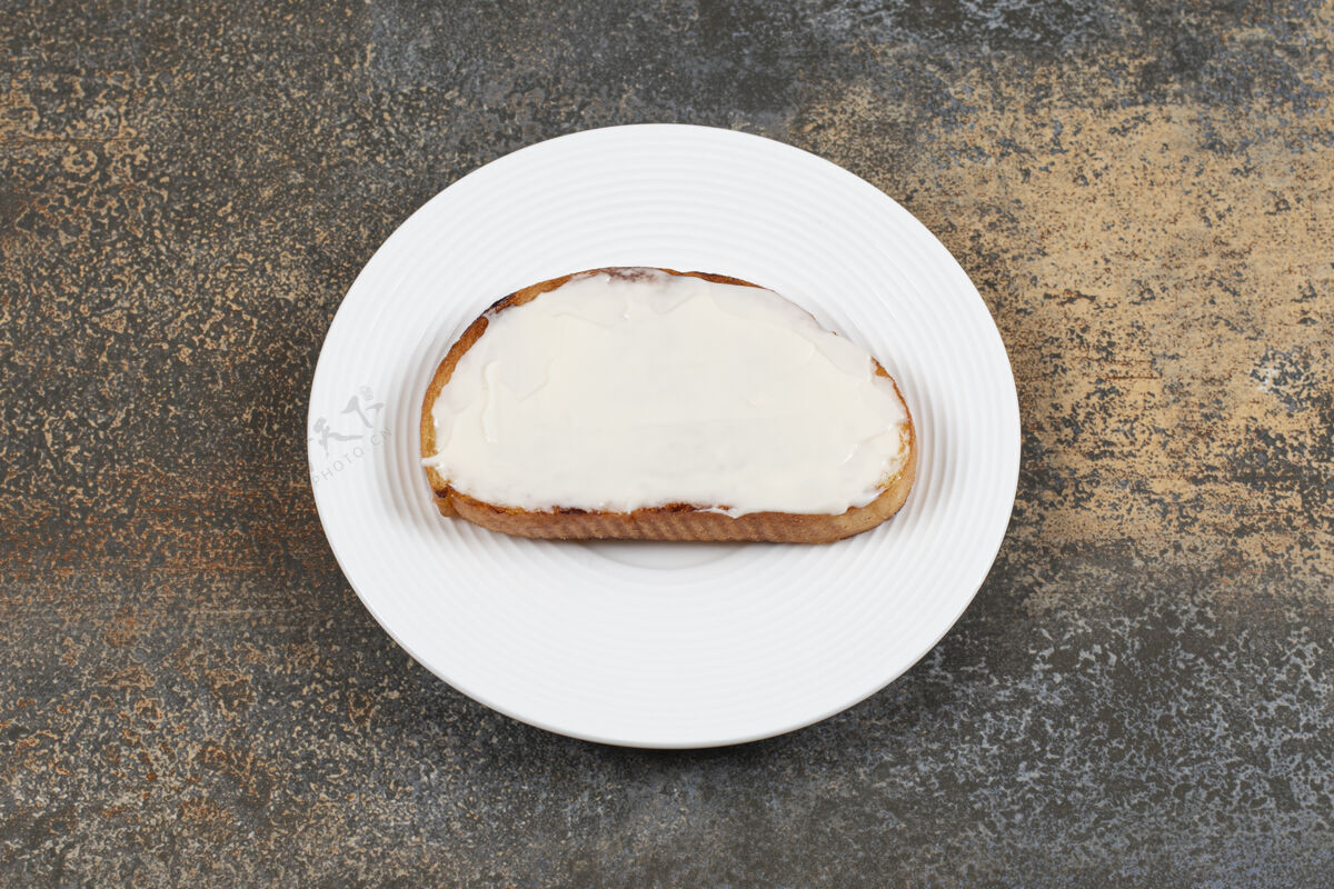 面包在白色盘子上放一片带酸奶油的烤面包片美味奶制品酸奶油