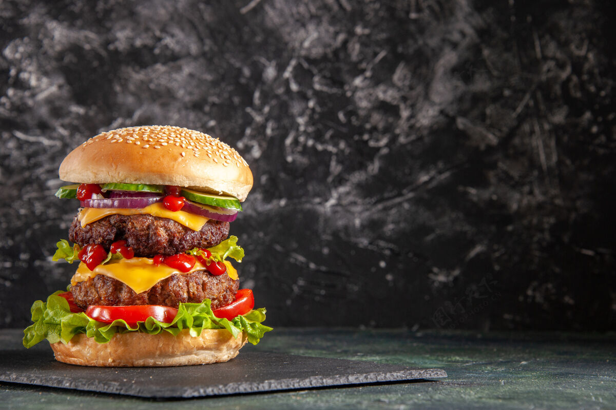 芝士汉堡美味的肉三明治和西红柿绿色的深色托盘在右边的黑色表面汉堡包晚餐面包
