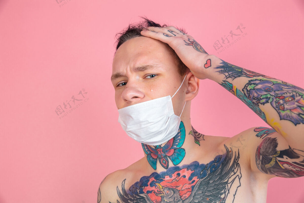 流行戴着面具粉色背景上的年轻怪人画像复制空间粉红纹身