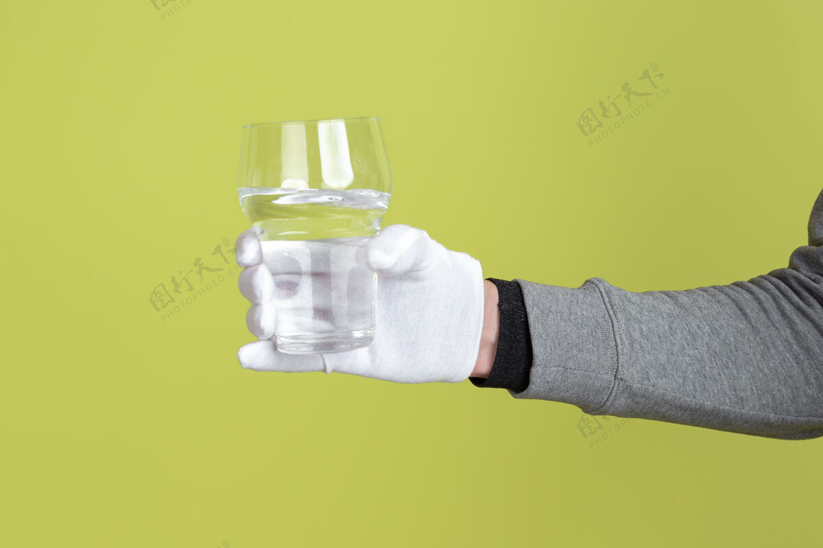 人男手戴白色防护手套 手拿纯水玻璃隔离在黄色墙上复制空间手套手
