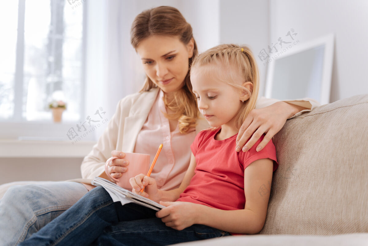 团结学校我是认真的漂亮聪明的女孩和妈妈坐在一起 一边做家务 一边在笔记本上写字女孩小学生传统