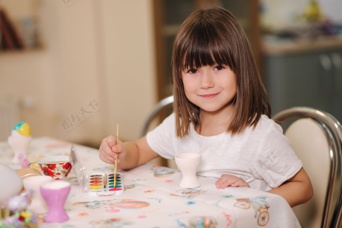 木头可爱的小女孩在家里打印复活节彩蛋美丽的女孩在准备复活节油漆鸡蛋里面