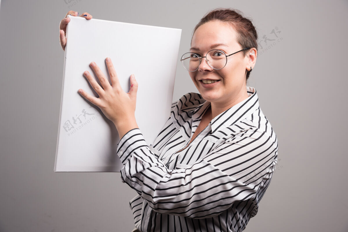 颜料女人在灰色的画布上展示她的白色空画布女人艺术家画布