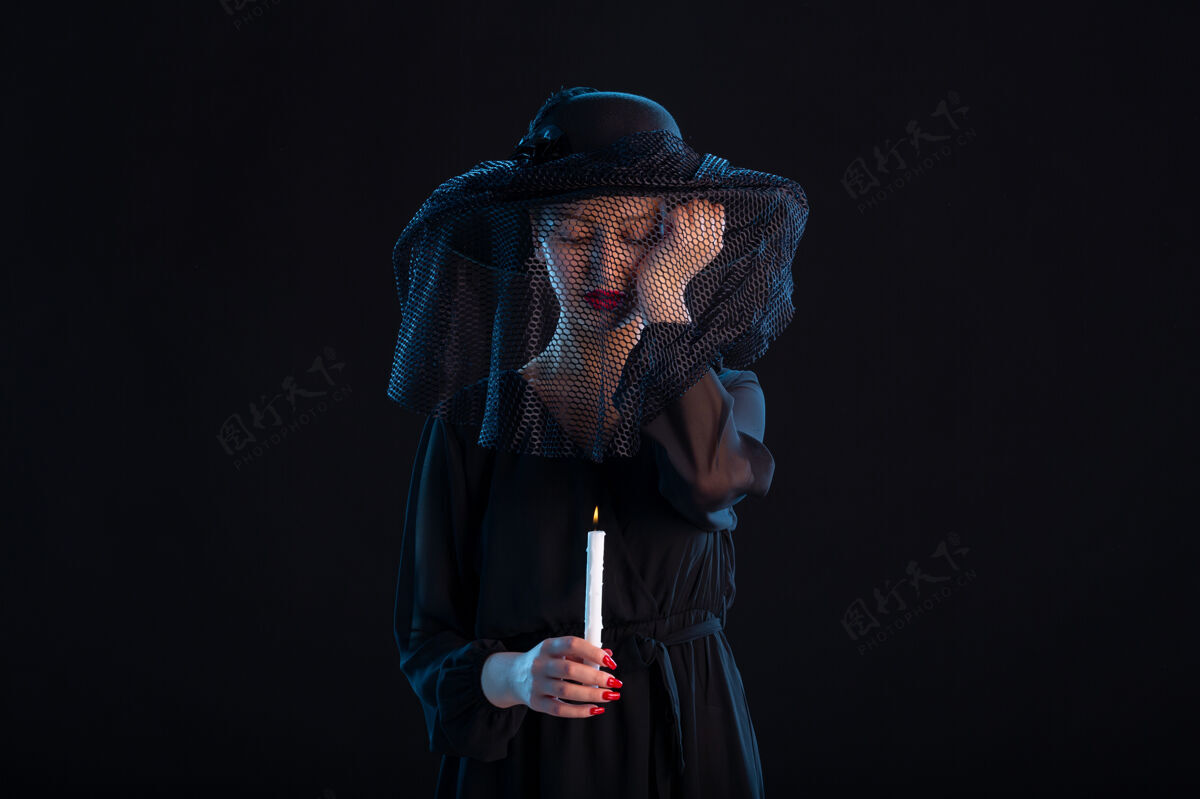 火悲伤的女性穿着黑色的衣服 在黑色的表面上燃烧着蜡烛悲伤的葬礼上死去女士衣服悲伤