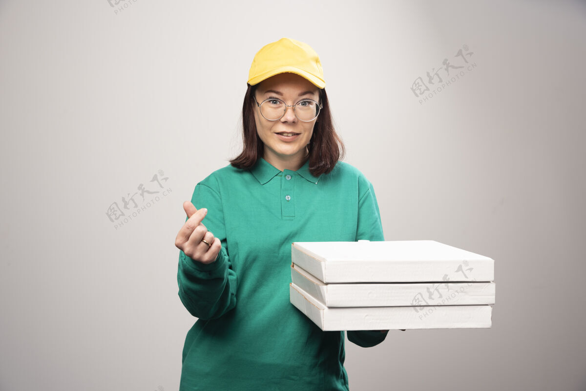 帽子女送货员拿着一张白色的高质量的比萨饼卡片年轻人食物送货
