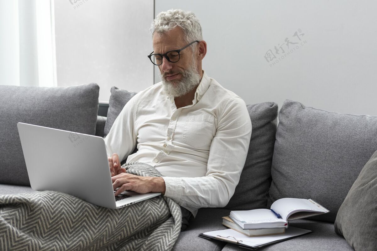 灰色头发家里的老人在沙发上用笔记本电脑学习老年人房子眼镜