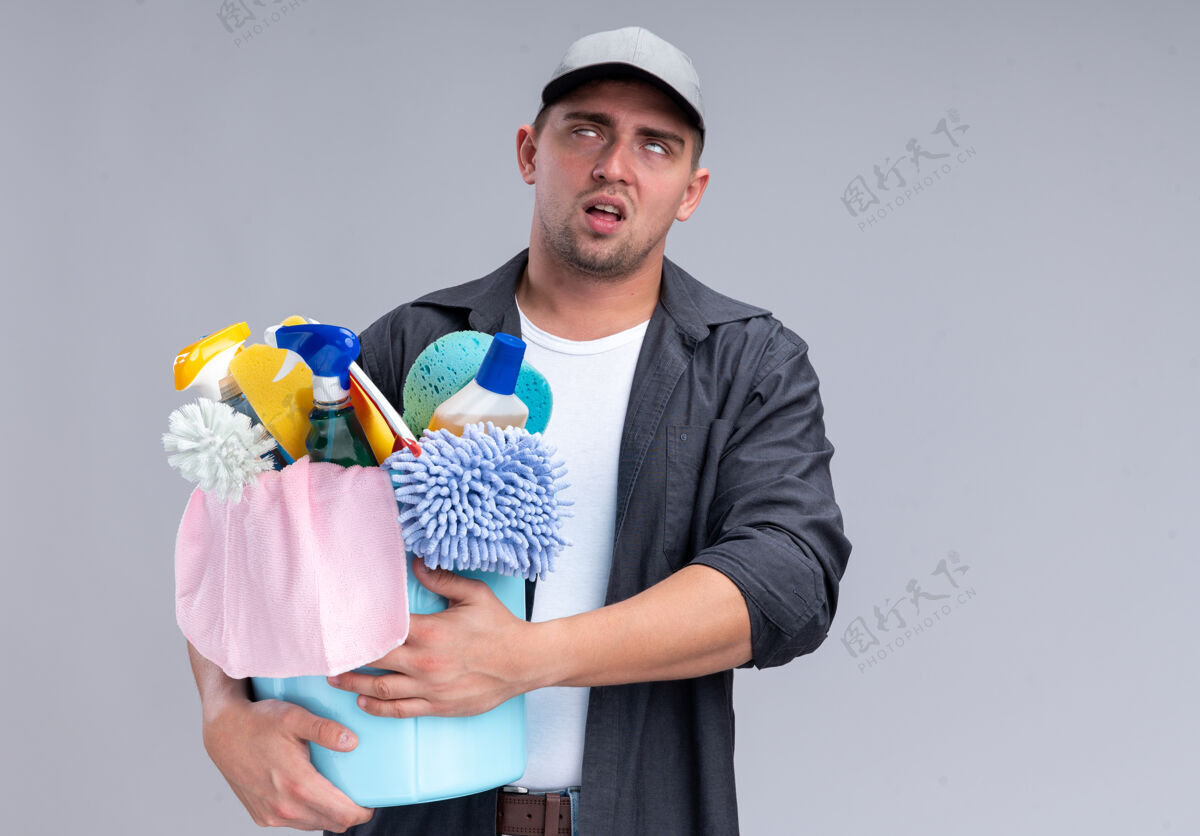 帽子疲惫不堪的年轻帅哥 穿着t恤 戴着帽子 手里拿着一桶清洁工具 隔离在白墙上 留着复印空间水桶帅哥穿着