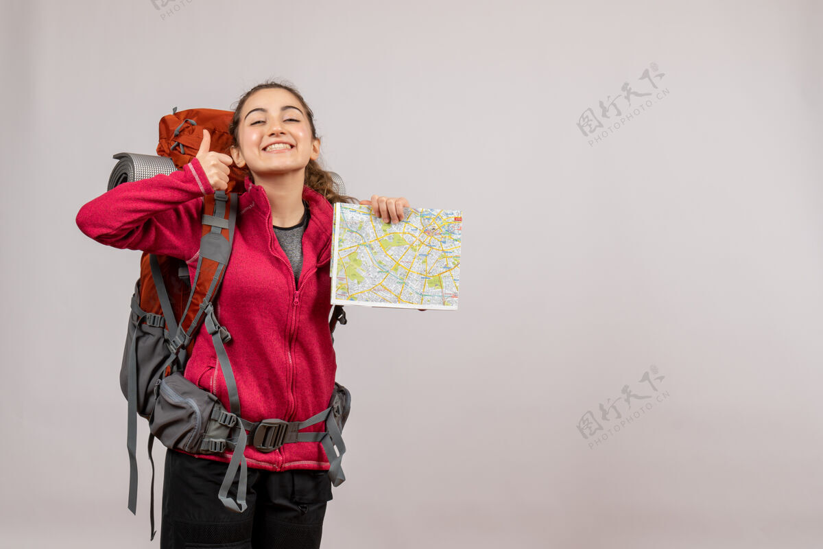 背包正面图年轻的旅行者背着大背包指着地图竖起大拇指成人灰色冒险