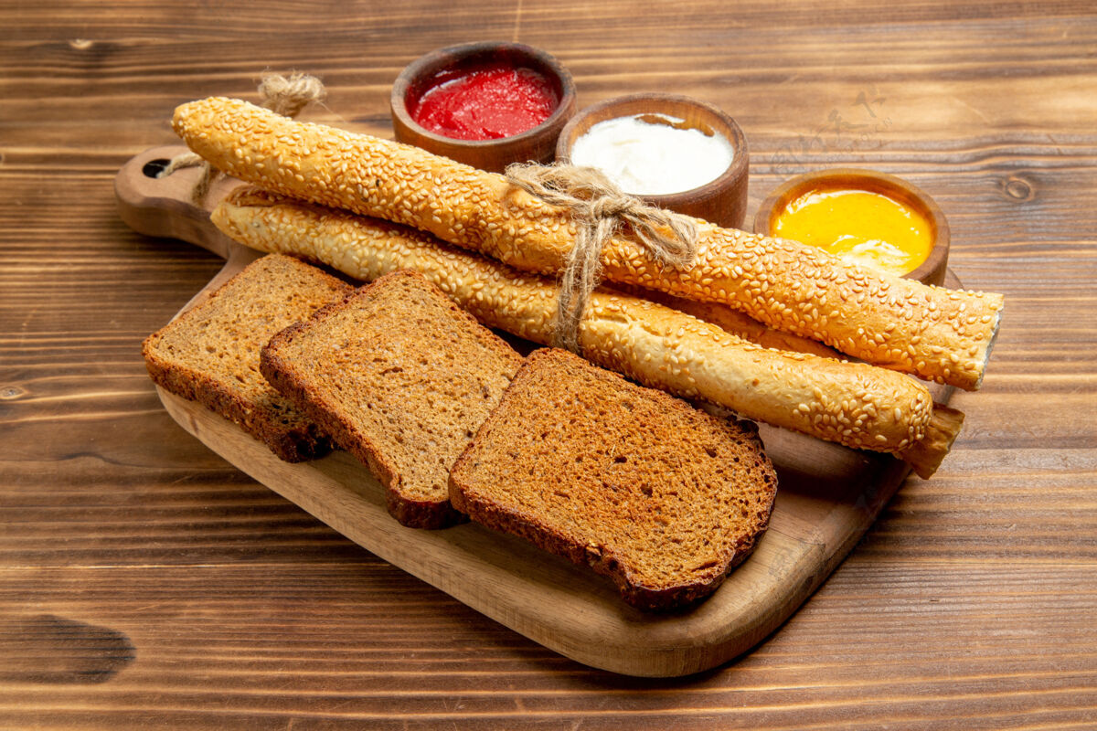 晚餐正面图深色面包面包 棕色桌子上有面包和调味品 食物面包 面包 辛辣调味品午餐美味