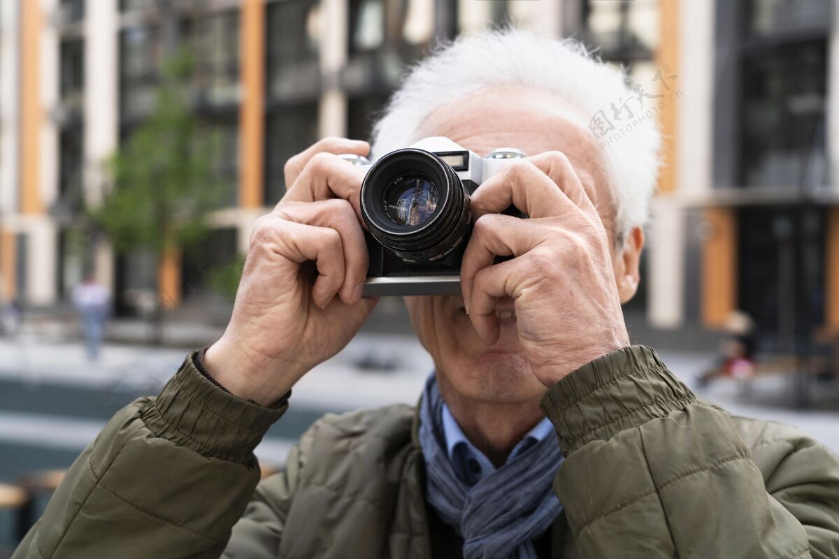城市时尚的老男人在城市里用相机拍照老年人成熟退休