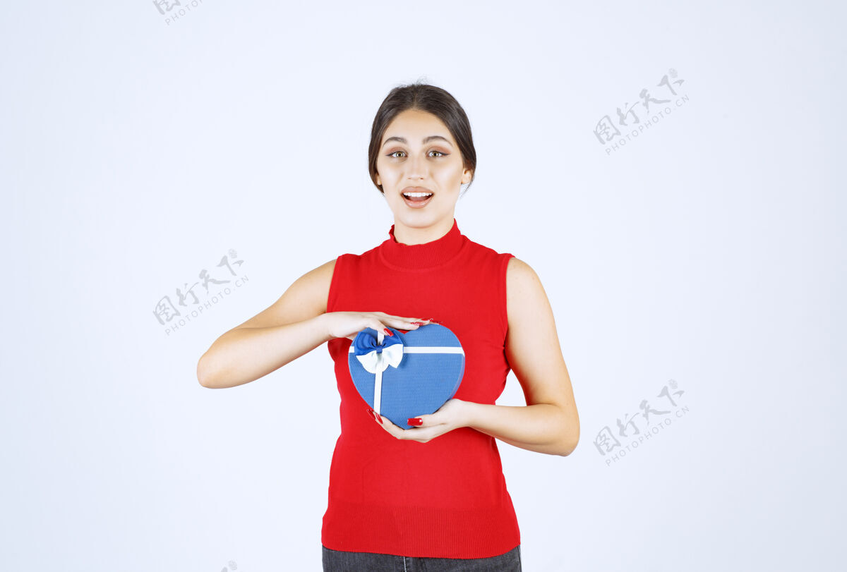 休闲穿红衬衫的女孩赠送她的蓝色心形礼盒工人年轻人庆祝
