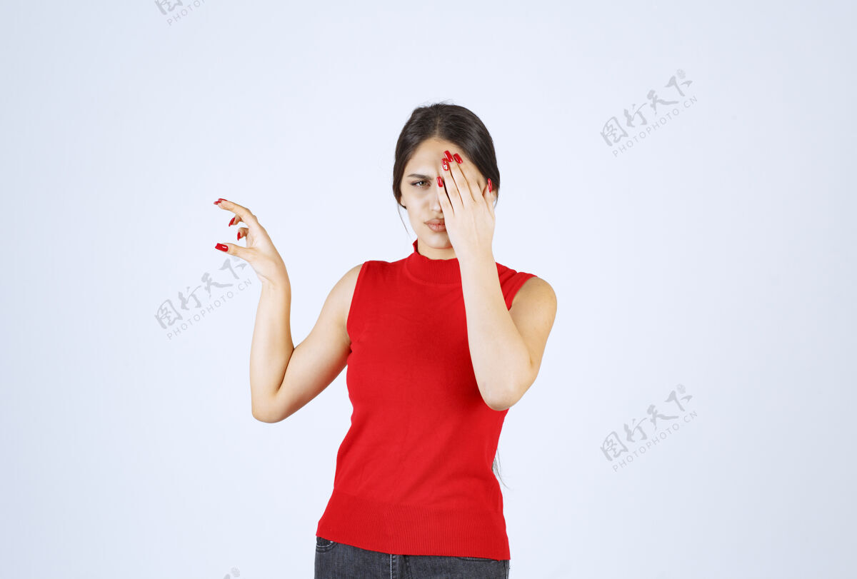 模特穿红衬衫的女孩透过手指看神秘服装符号