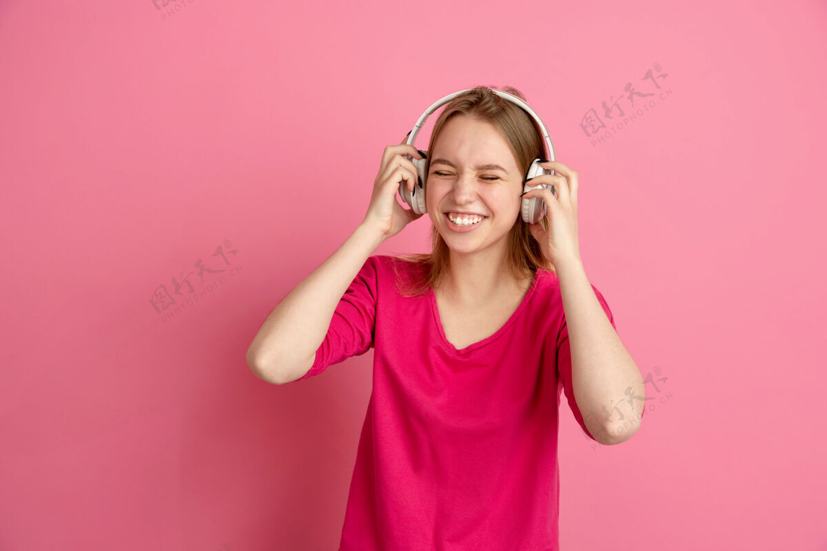 表达听音乐 快乐白种人年轻女子的画像孤立在粉红色的墙上 单色美丽的女模特人肖像长度