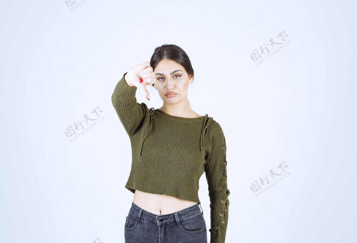 向下一个悲伤的年轻女子站着 拇指朝下的照片人类悲伤女人