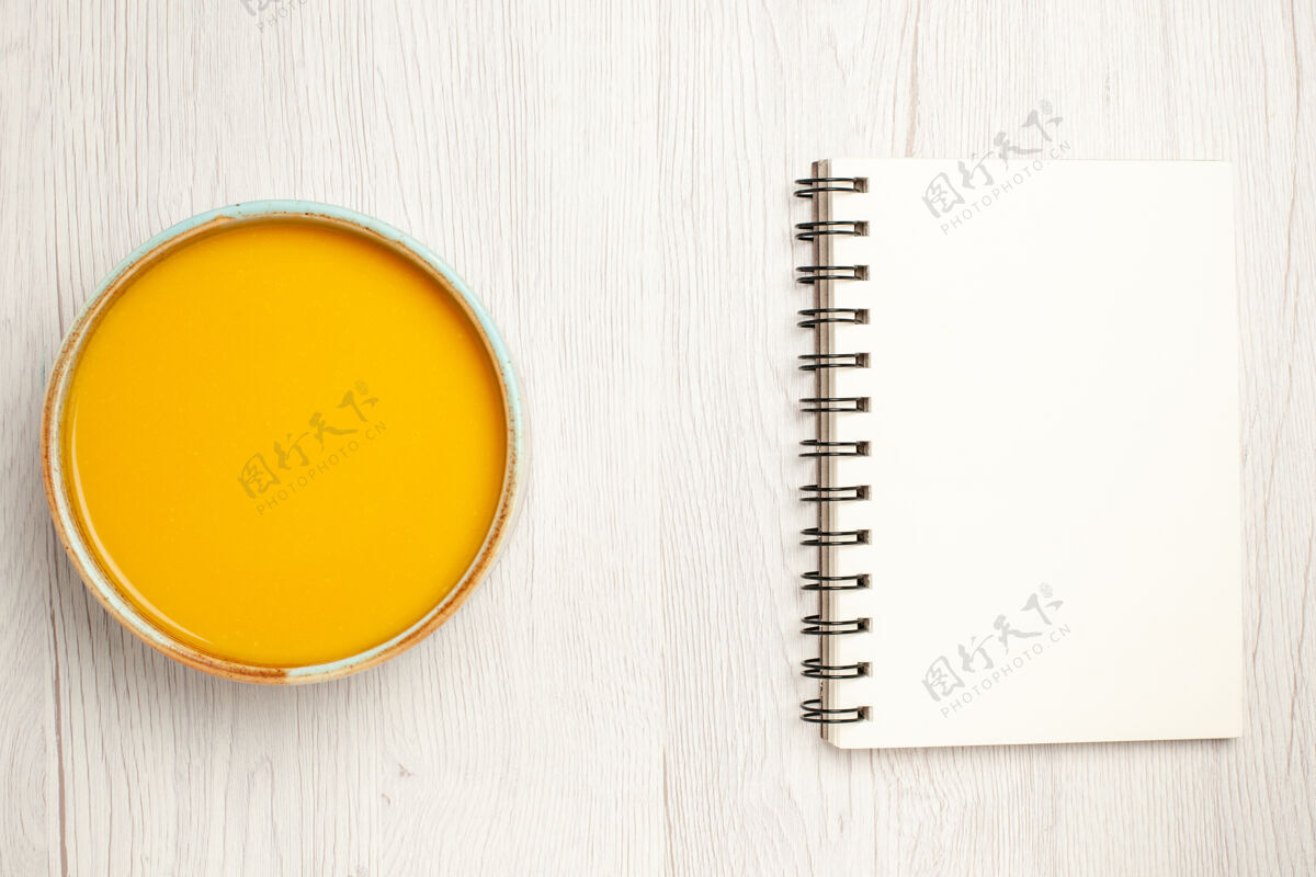 仪器俯瞰美味的奶油汤黄色的汤白色桌面上的记事本汤酱饭奶油菜晚餐记事本酱汁笔记本