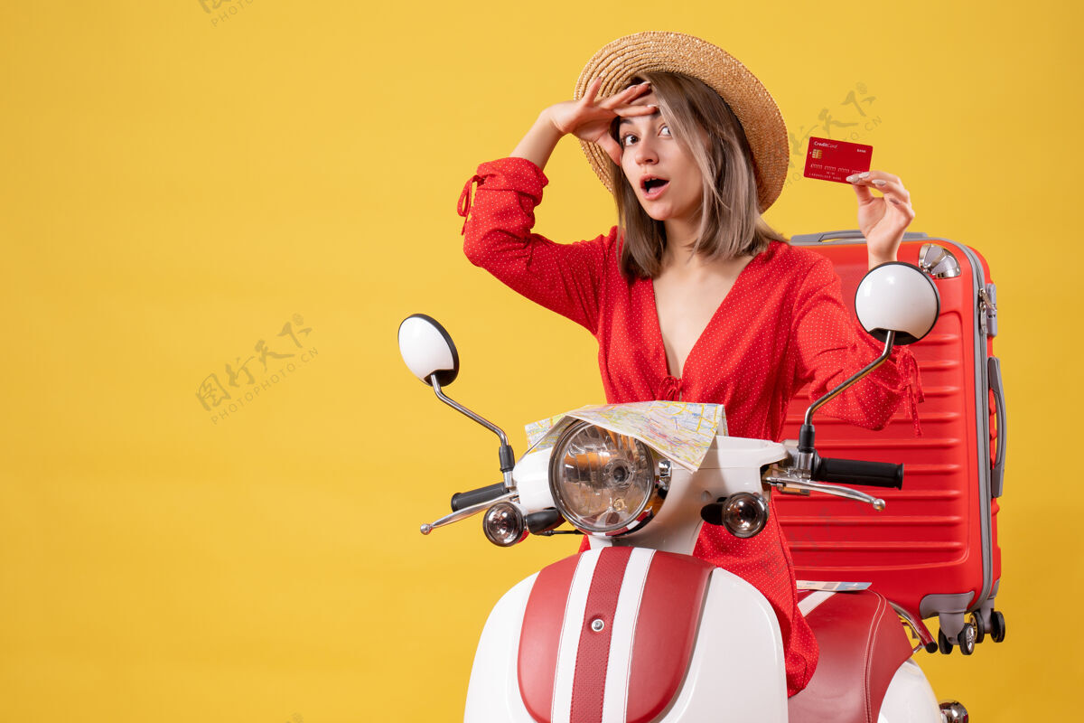 行李正面图：穿着红裙子的年轻女士 手推车上拿着银行卡付款旅游旅行者