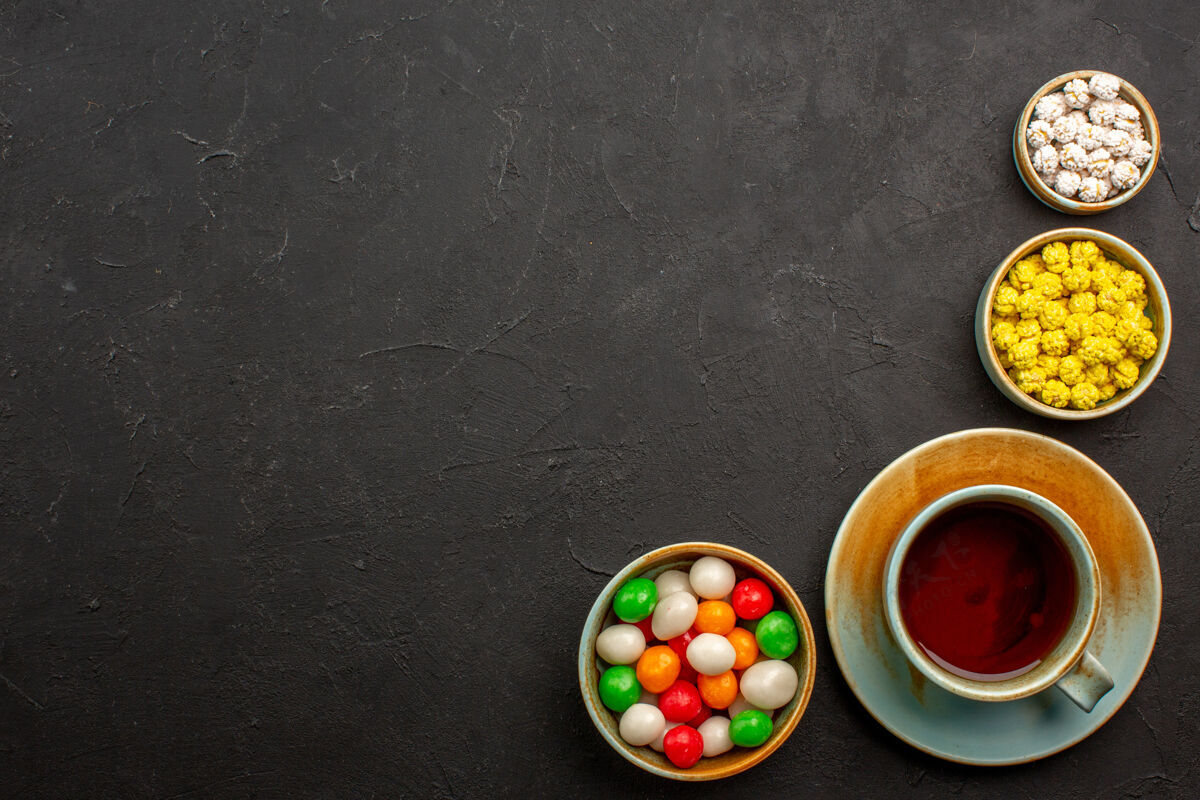容器顶视图茶杯上的糖果茶色彩虹糖深色办公桌赌博盘子传统