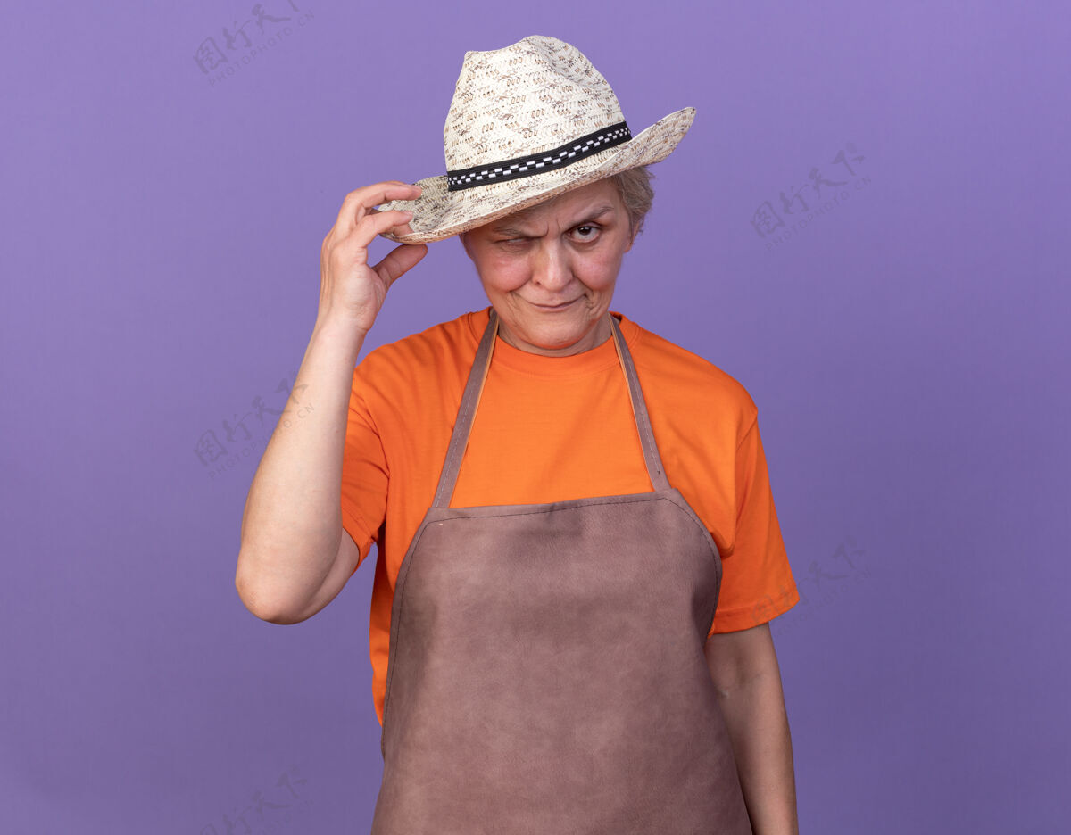 园艺自信的上了年纪的女园丁戴着园艺帽看着镜头穿老人帽子