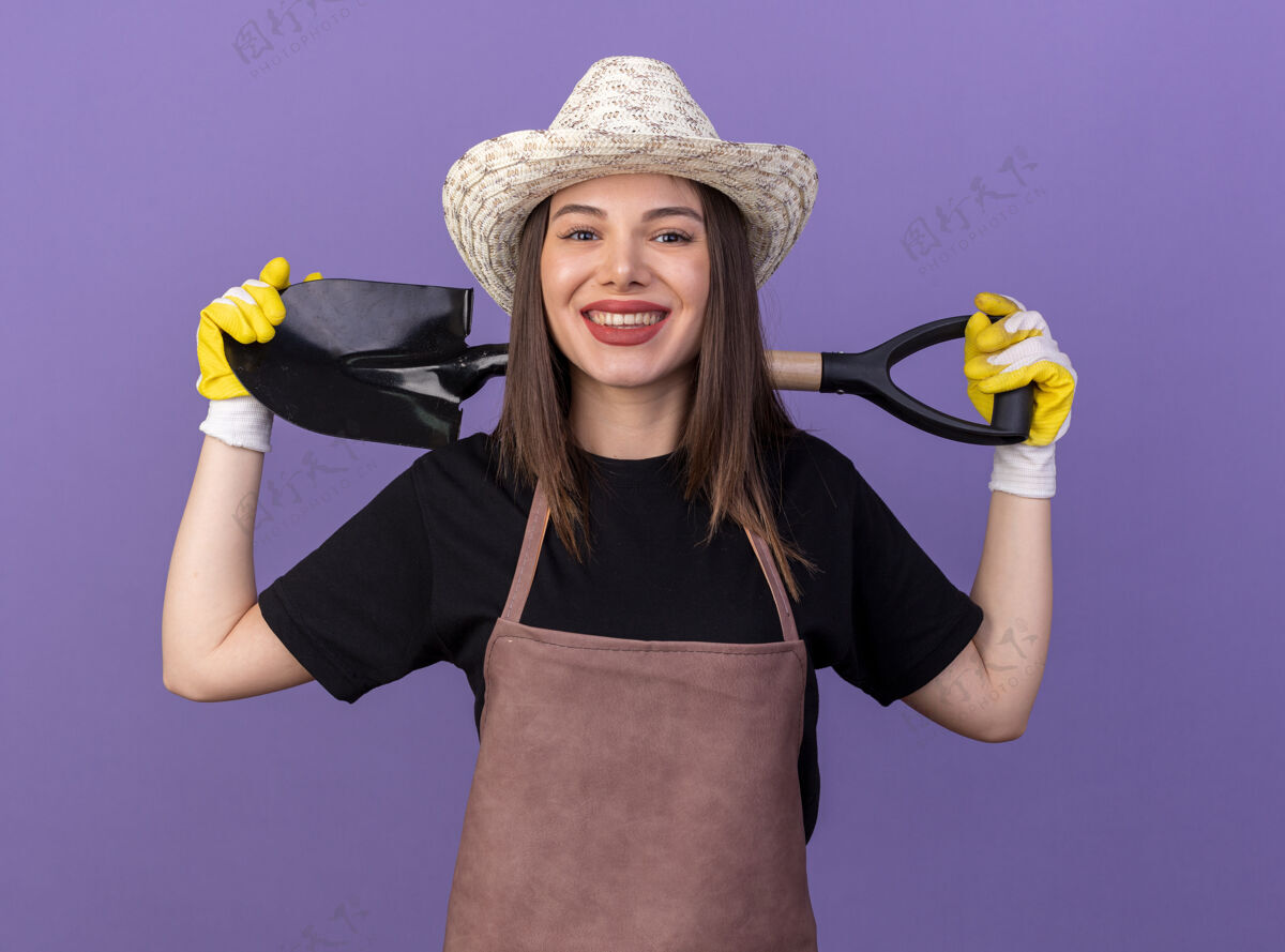 微笑面带微笑的白人女园丁戴着园艺帽和手套 背后脖子上拿着铲子手套脖子帽子