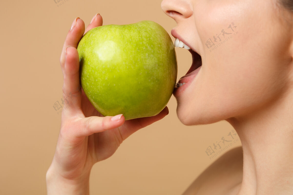 饮食特写黑发半裸完美皮肤的女人 裸妆把苹果隔离在米色粉彩墙上恢复活力排毒感官