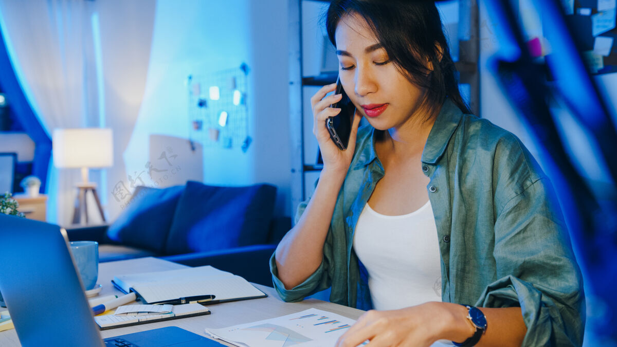 疲倦亚洲自由职业女性使用笔记本电脑通话繁忙的企业家在客厅远距离工作互联网拉丁语专业人士