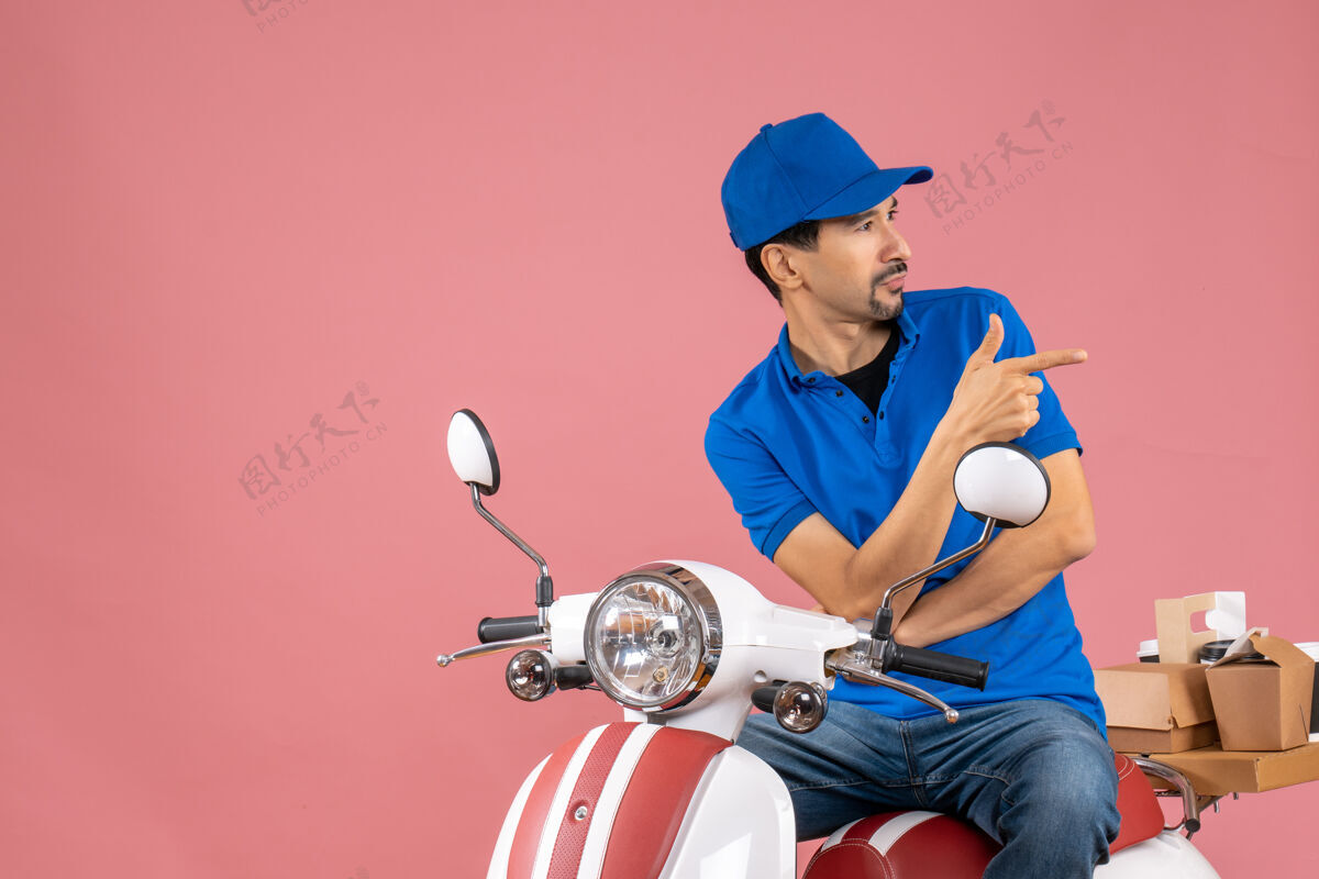 坐顶视图好奇的快递员戴着帽子坐在滑板车上传递粉彩桃色背景的命令人物粉彩头盔