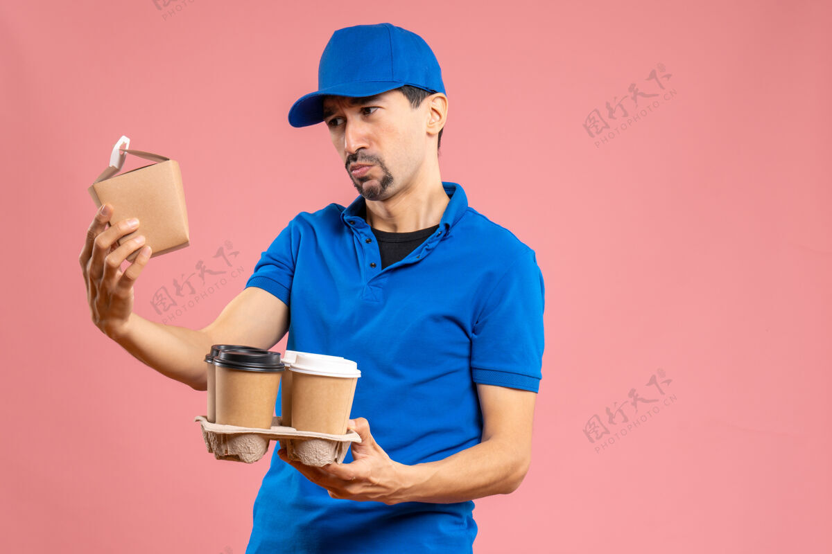工作正面是情绪集中的男性送货员戴着帽子拿着订单持有雇员服务员