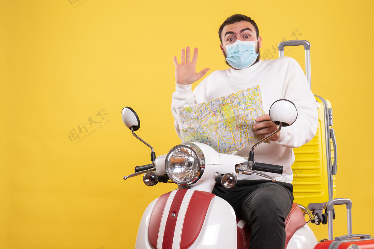 车辆旅行概念的俯视图 戴着医用面罩的惊讶的家伙坐在摩托车上 黄色手提箱放在上面 手里拿着地图顶黄色旅行