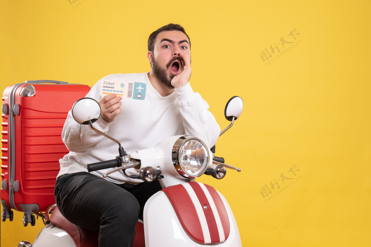 球员俯视图：年轻的旅行男子坐在摩托车上 手提箱放在上面 手里拿着车票 叫着黄色的人运动员呼叫手提箱