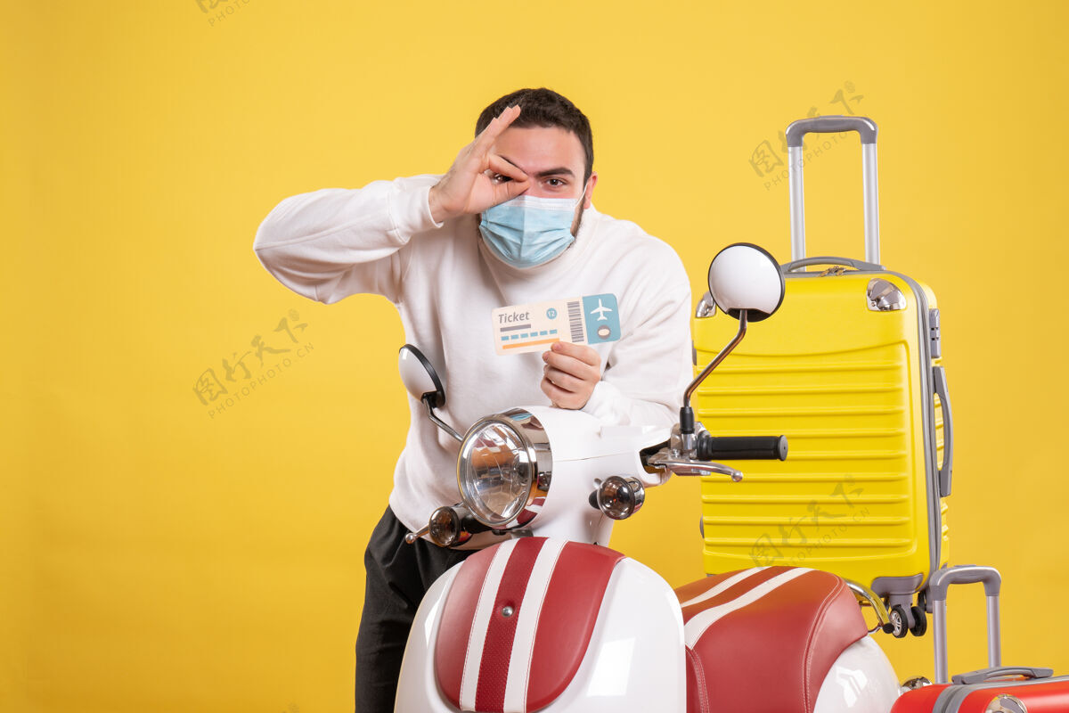 摩托车旅行概念的顶视图 戴着医用面罩的自信的家伙站在摩托车旁边 黄色手提箱在上面 手里拿着车票票男性体育