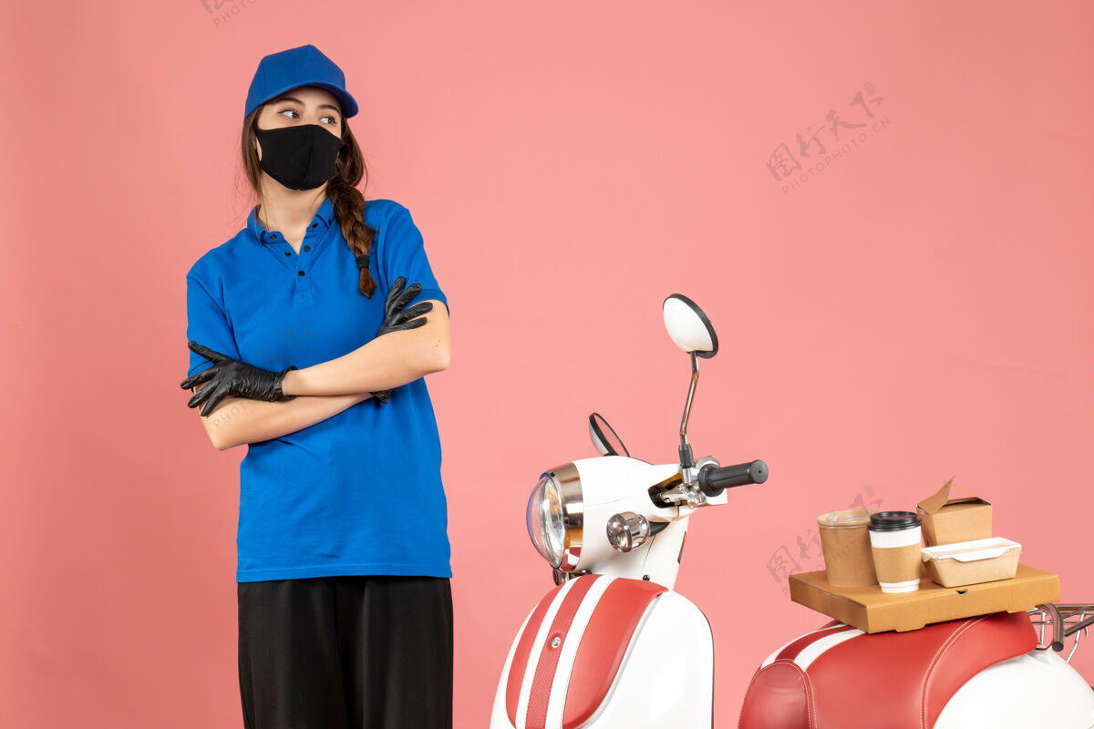 粉彩俯视图：贴心的信使女孩戴着医用面罩站在摩托车旁 粉色的咖啡蛋糕医疗比赛观点