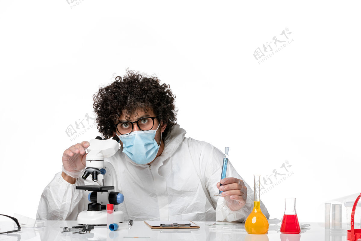 医学男医生穿着防护服 戴着口罩 用显微镜对着一个白色的防护显微镜男医生