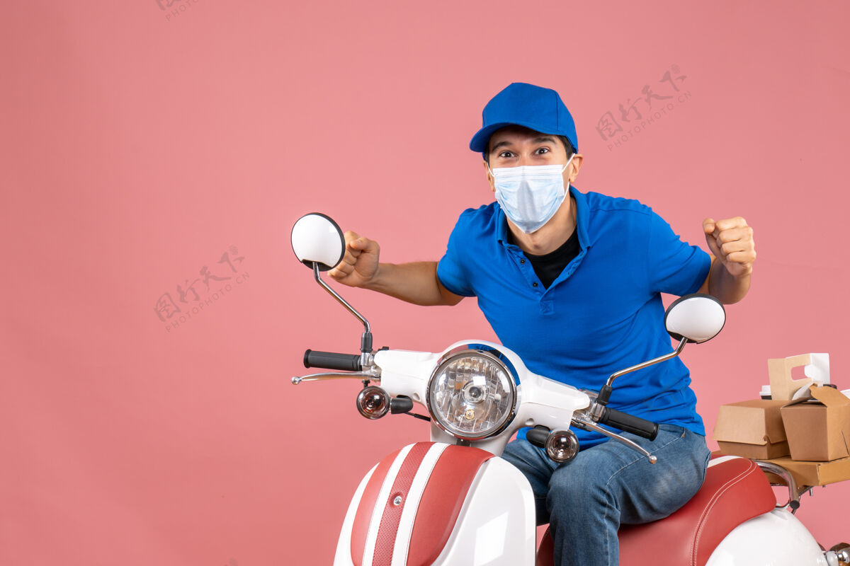 医疗前视图愤怒紧张的快递员戴着医疗面具戴着帽子坐在粉彩桃色背景的踏板车上快递员人滑板车