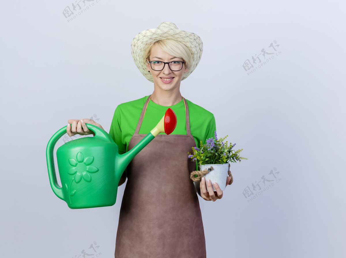短裤年轻的园丁 围裙短发 戴着帽子 手里拿着水罐和盆栽 满脸笑容微笑脸帽子