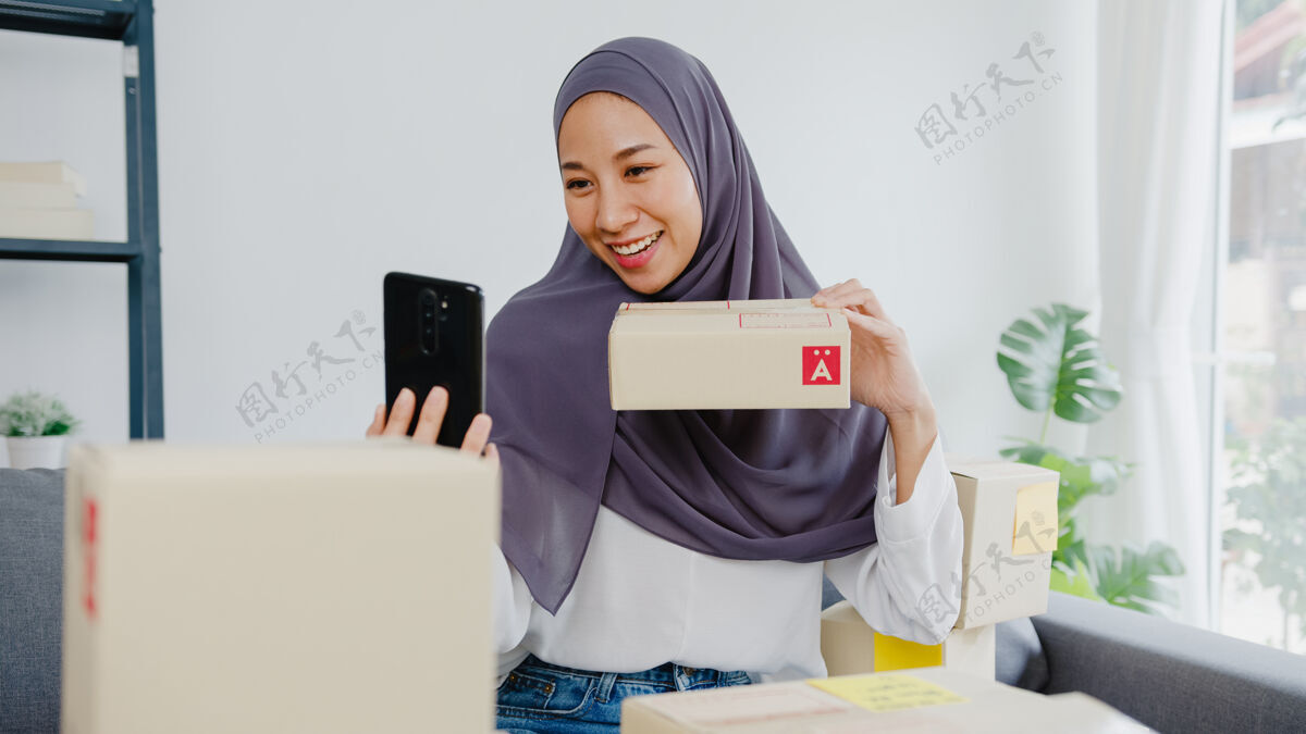 购买年轻的女商人博客使用手机摄像头录制vlog视频直播审查产品在家办公电子商务订单阿拉伯语