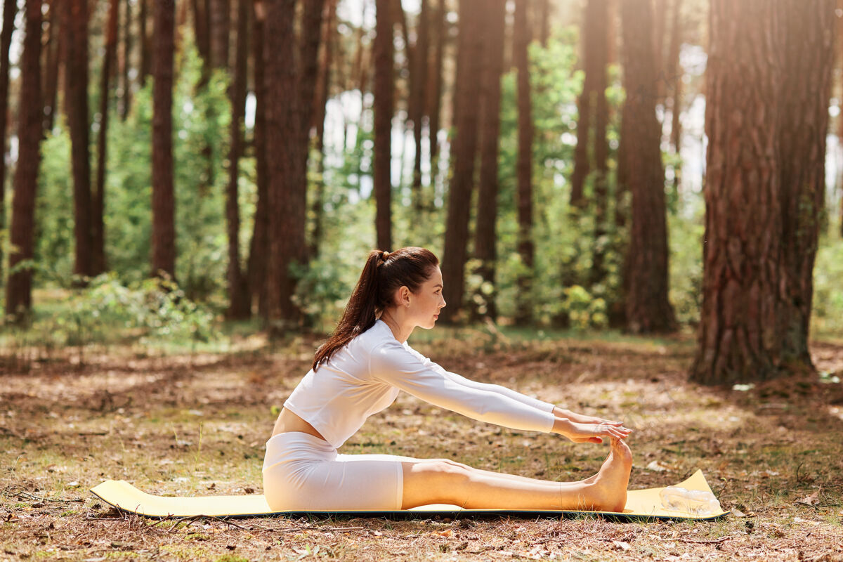 女孩户外仰卧起坐运动服侧视图 森林瑜伽训练 自然锻炼 放松冥想 健康生活方式上衣身体姿势