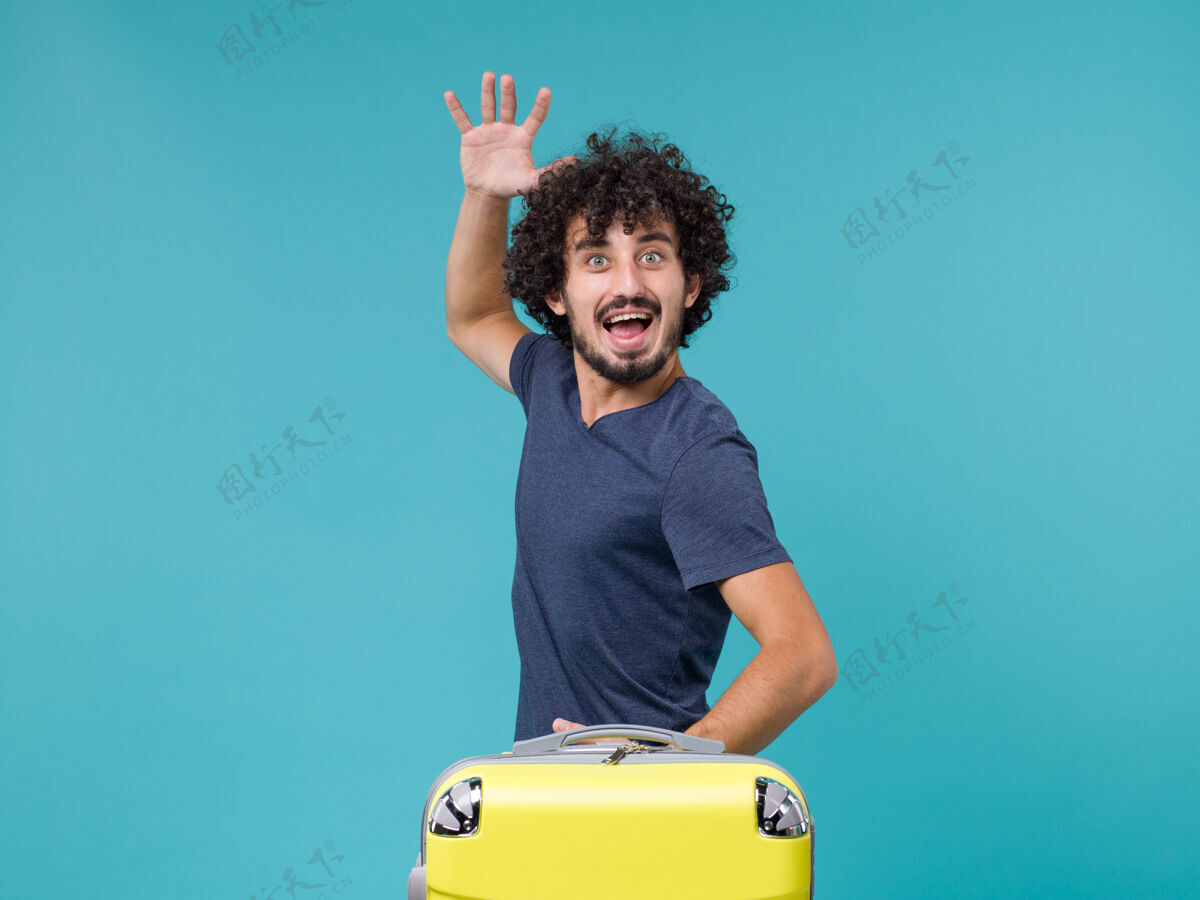 黄带着黄色手提箱度假的男人在蓝色上感到快乐包感情旅行