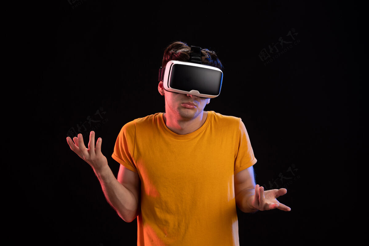 成人戴着vr耳机的年轻人在黑暗的墙壁上的正面视图男性虚拟现实男人