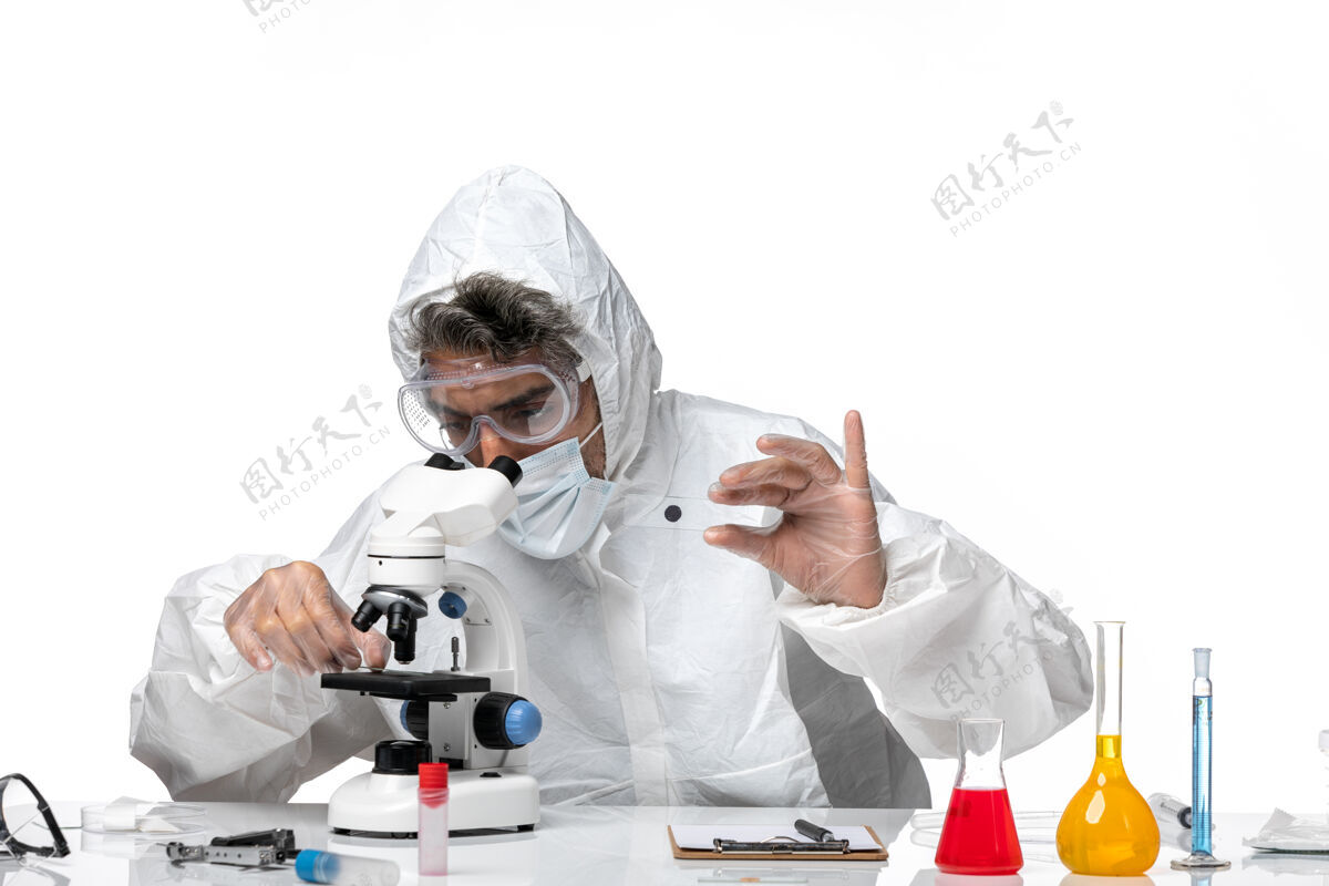 显微镜男医生穿着防护服 带无菌口罩 用显微镜观察浅白色医学视图医生