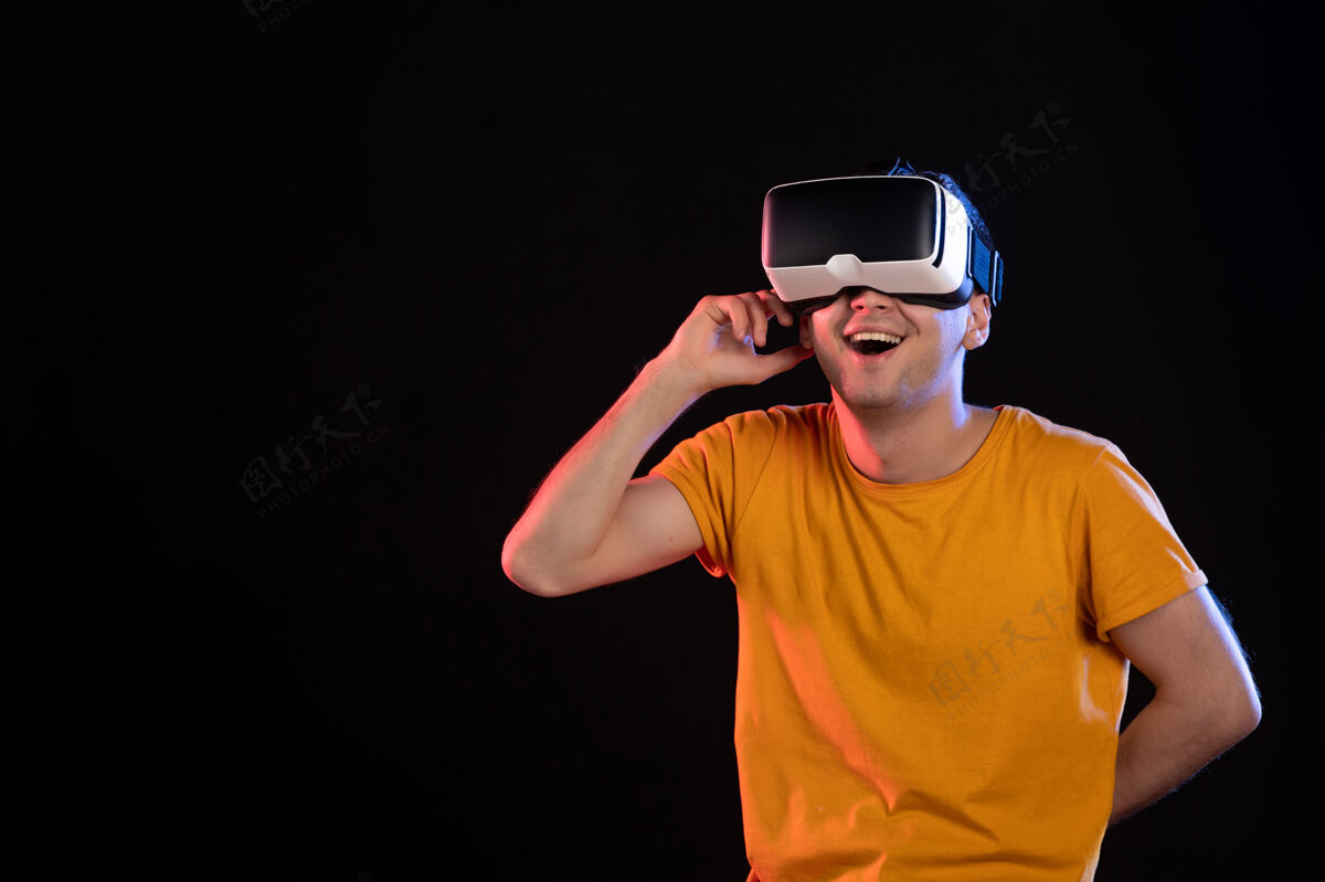 游戏在黑暗的墙壁上玩虚拟现实的年轻男性的正面视图男人视觉年轻男性