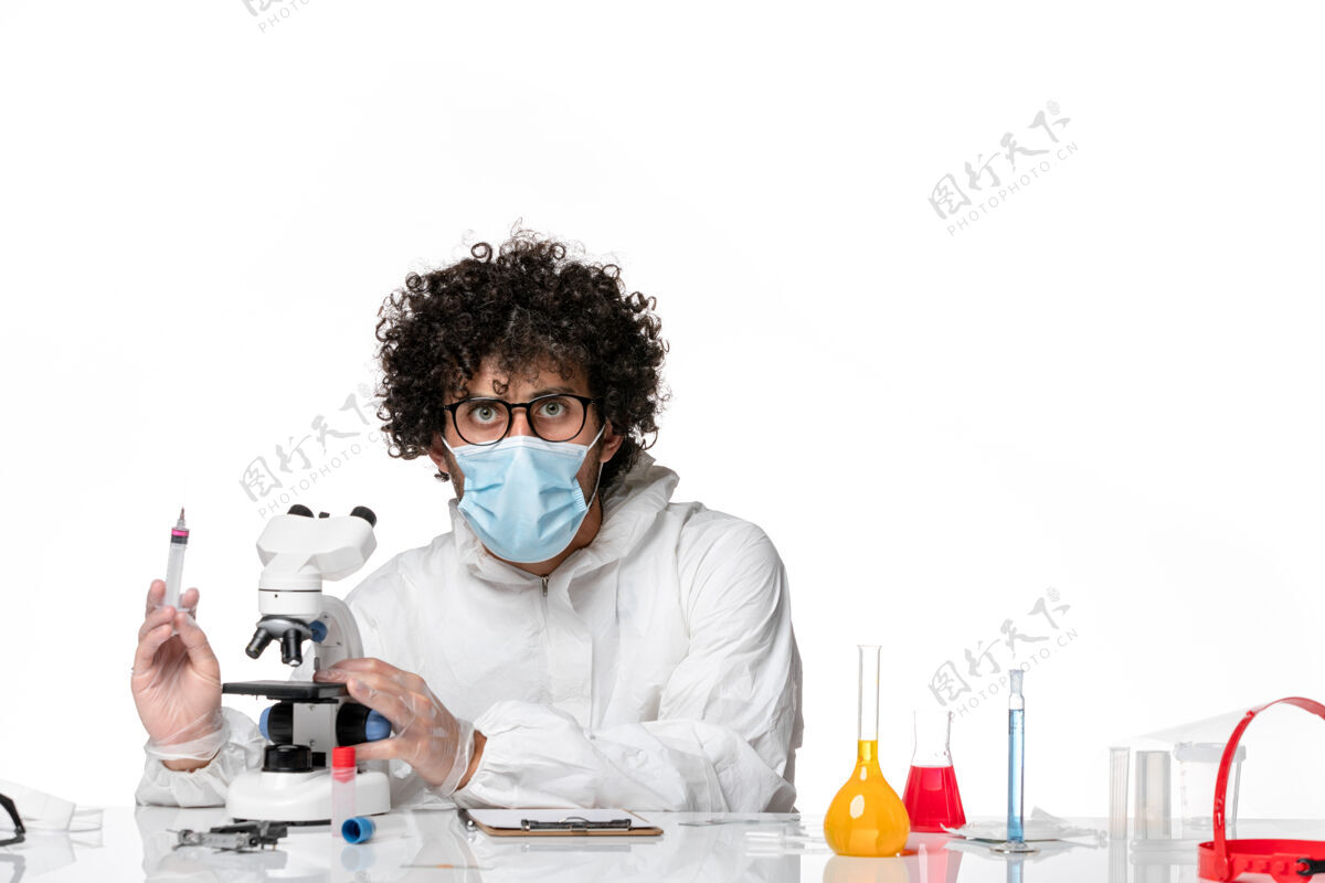 实验室外套男医生穿着防护服 戴着口罩 用显微镜对着白色使用外套面具